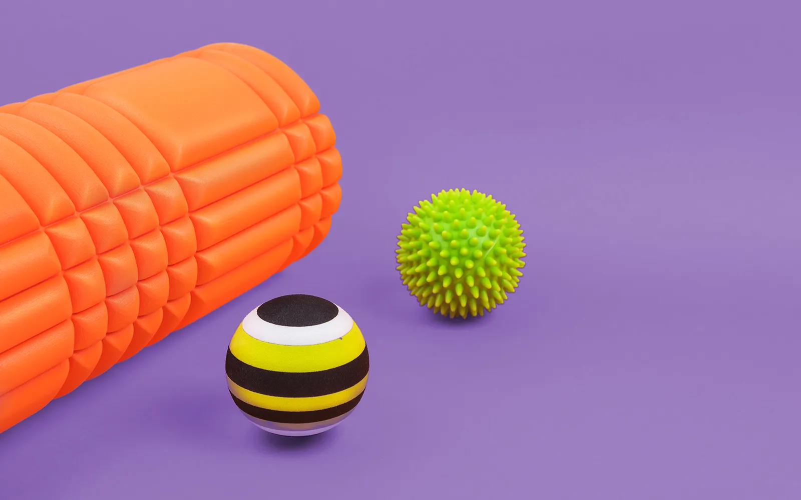 WIN_25_SavvySelfCare_Main A neon orange foam roller and two different kinds of therapy balls.